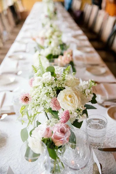 A long banquet table set with flowers and glassware